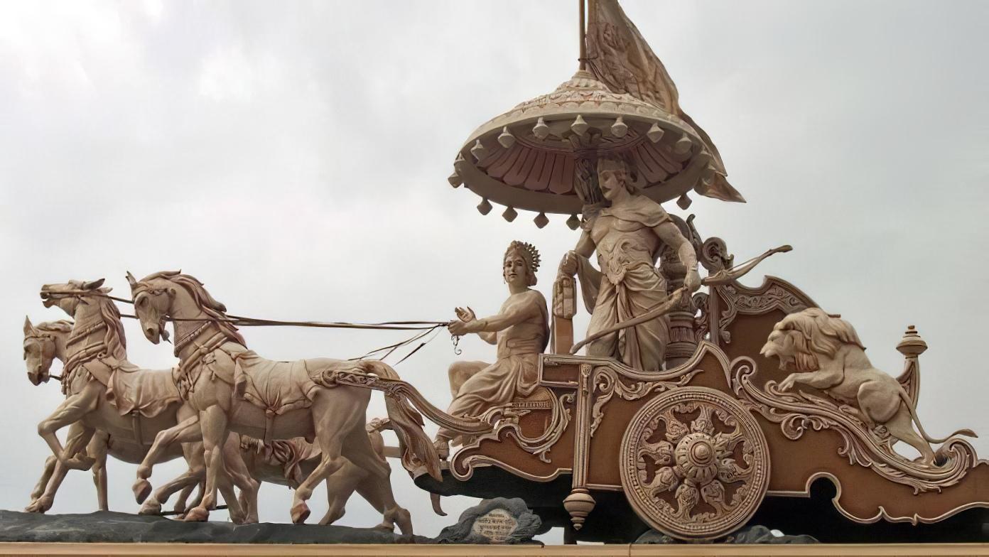 Sculpture représentant un char védique tiré par des chevaux avec un cocher tenant les rênes et un passager à l'arrière.